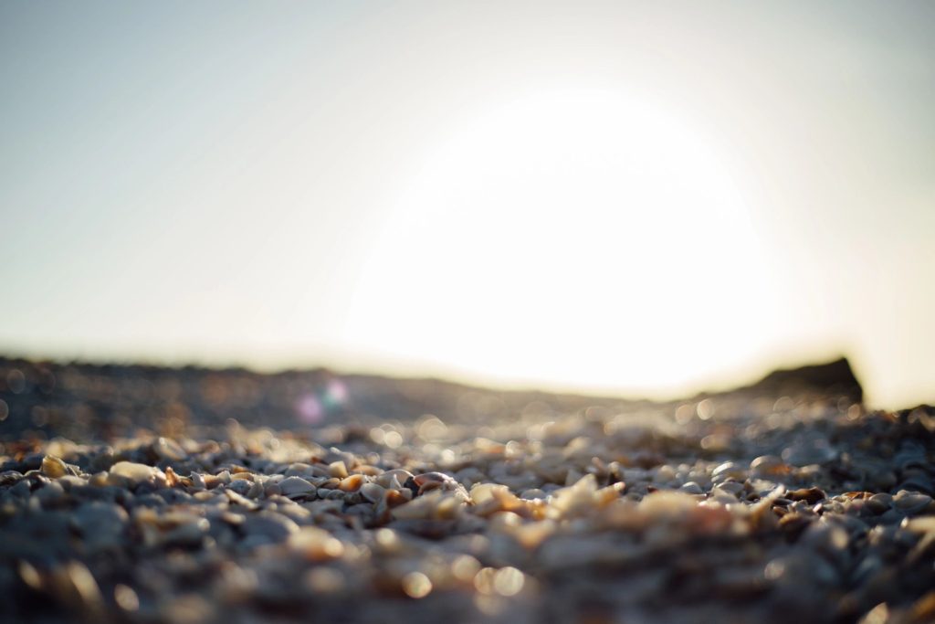 A close up of the sun setting over some sand