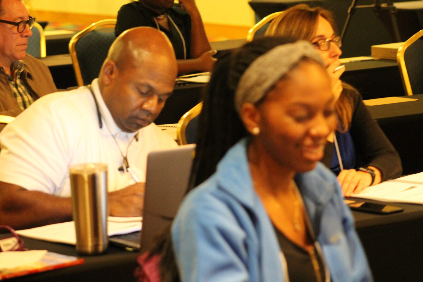 A group of people sitting at tables with laptops.