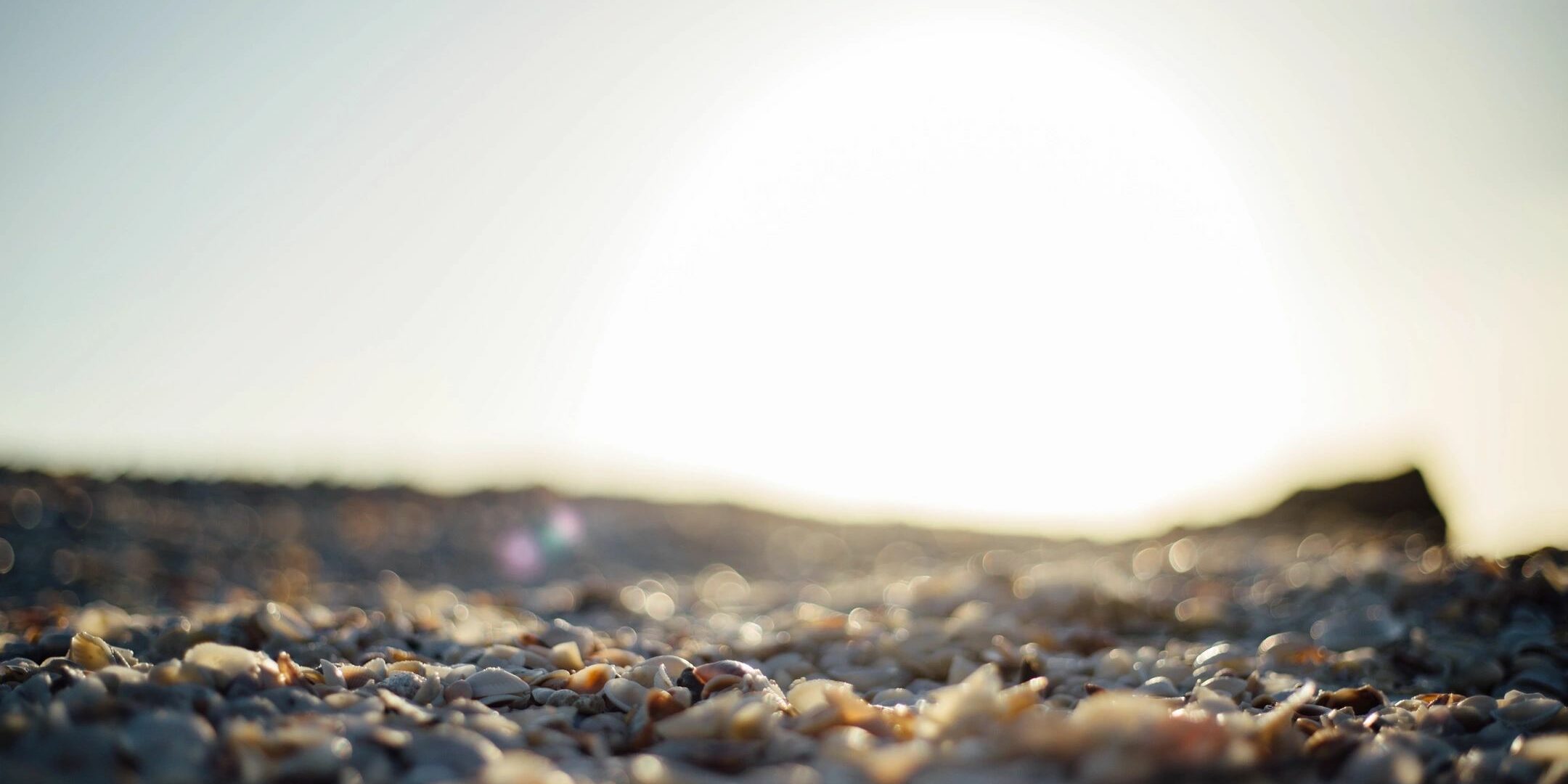 A close up of the sun setting over some sand